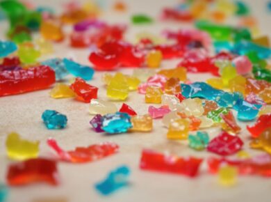 Bunte Gelee-Sticks, einige zerbrochen, auf neutralem Untergrund.