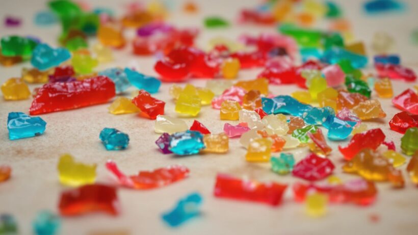 Bunte Gelee-Sticks, einige zerbrochen, auf neutralem Untergrund.