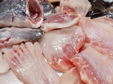 Rohe Fischfilets auf Edelstahloberfläche mit Eiskristallen.