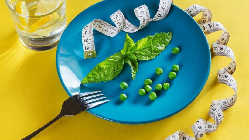 a blue plate topped with green vegetables and measuring tape