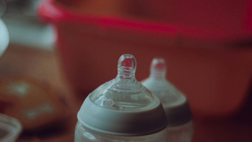 clear plastic feeding bottle on red table